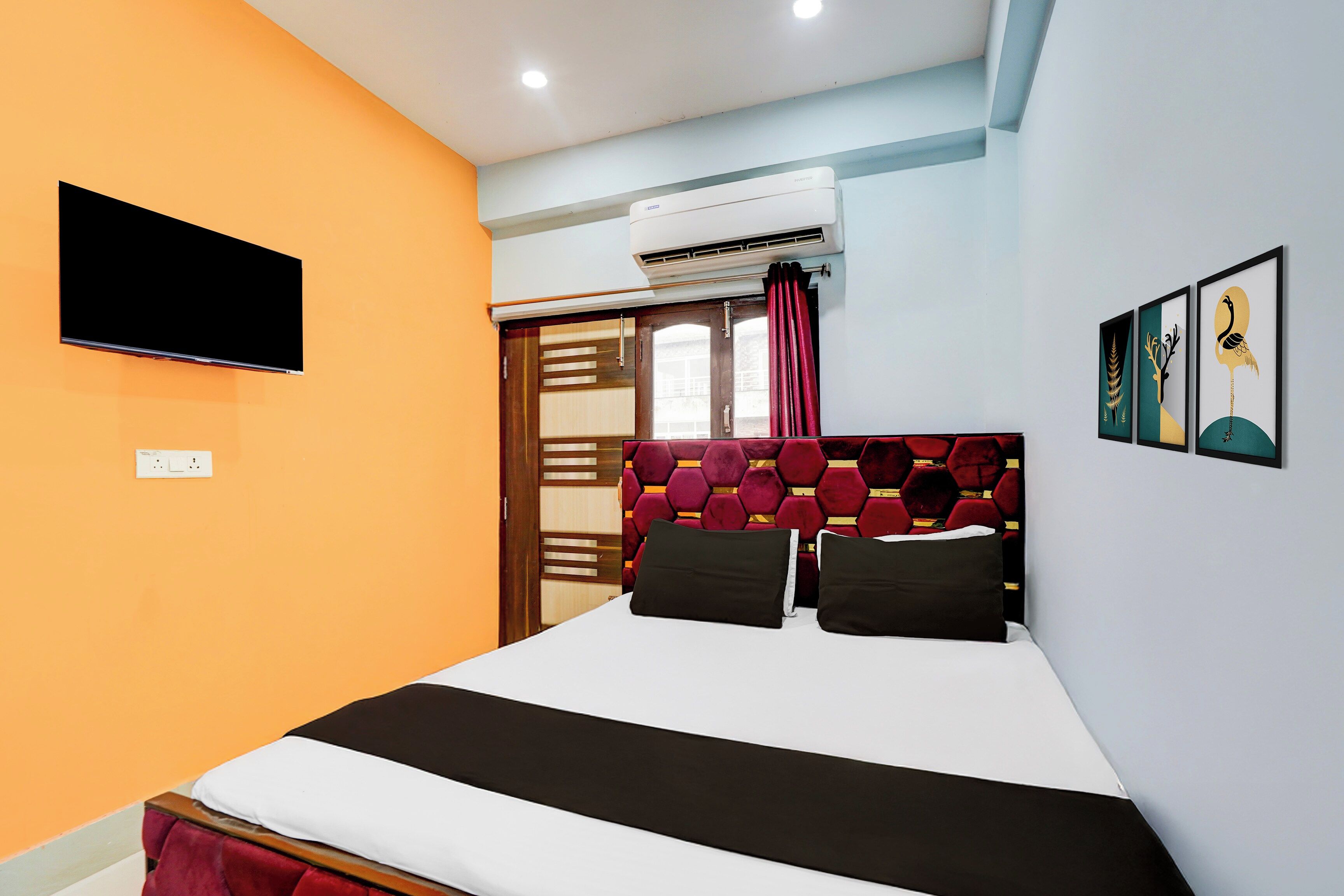 Habitación de hotel con una cama, un televisor de pantalla plana en la pared y obras de arte en la pared.