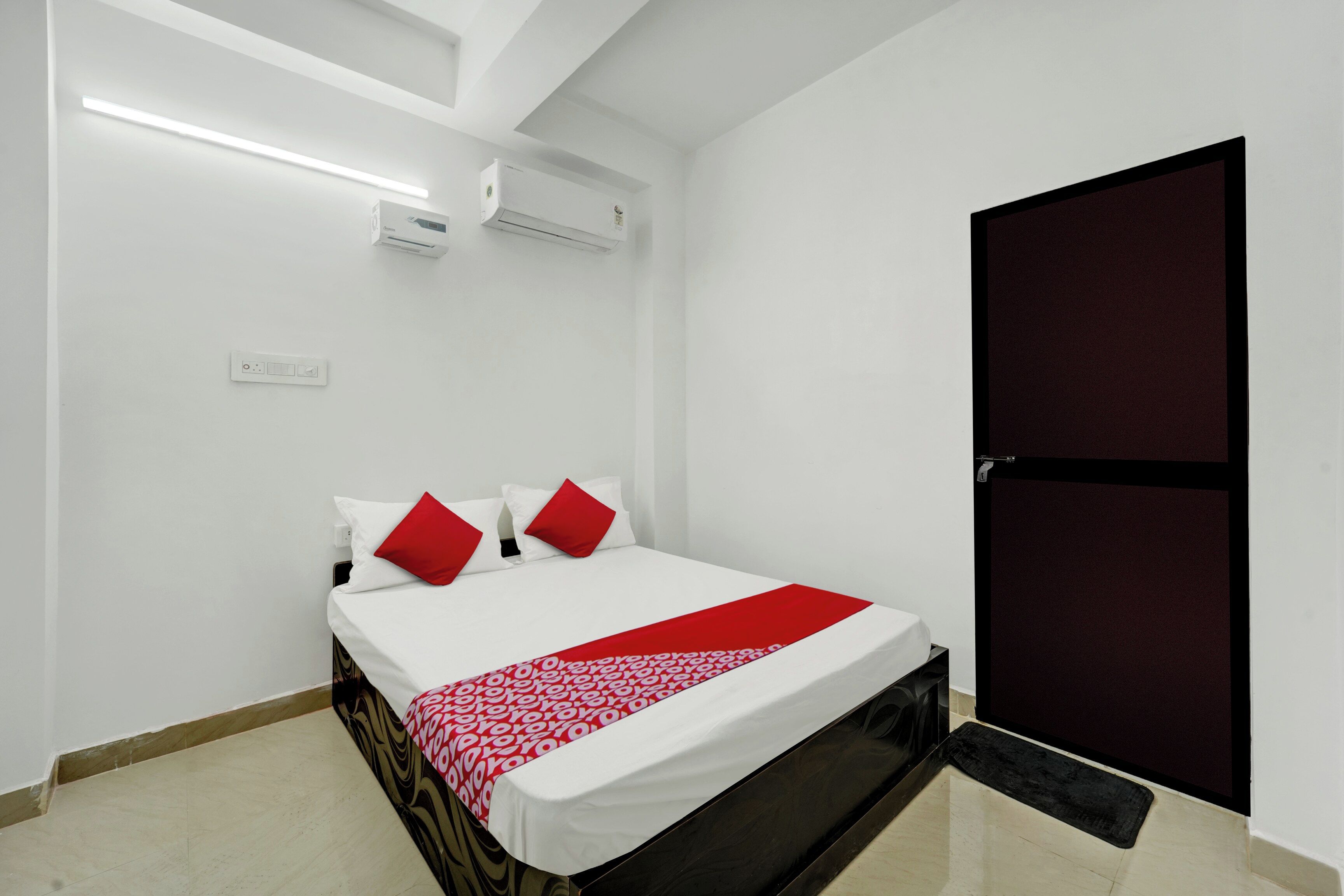 A hotel room with a bed, a wardrobe, a bedside table, and a wall-mounted air conditioner.