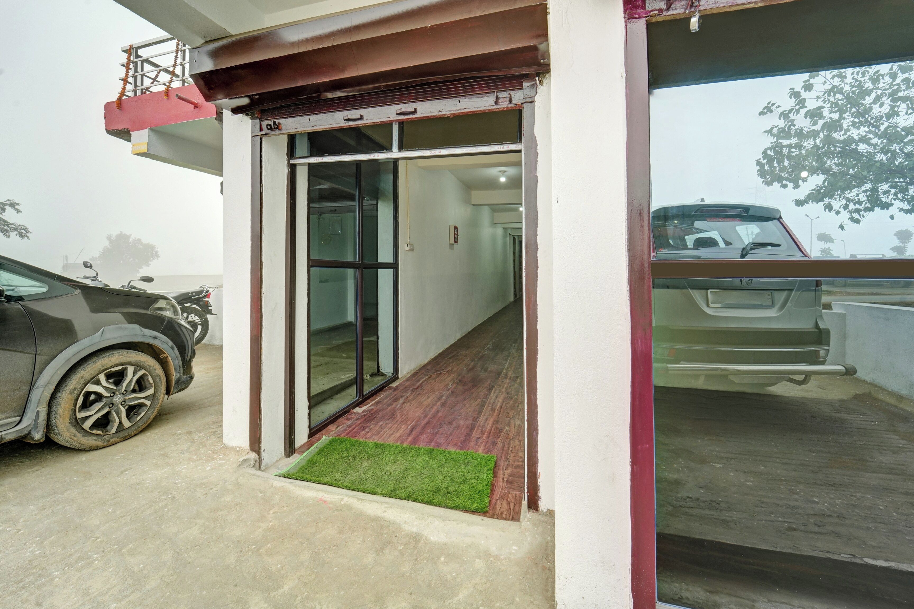 A building entrance with a glass door, a concrete floor, and a small green mat.