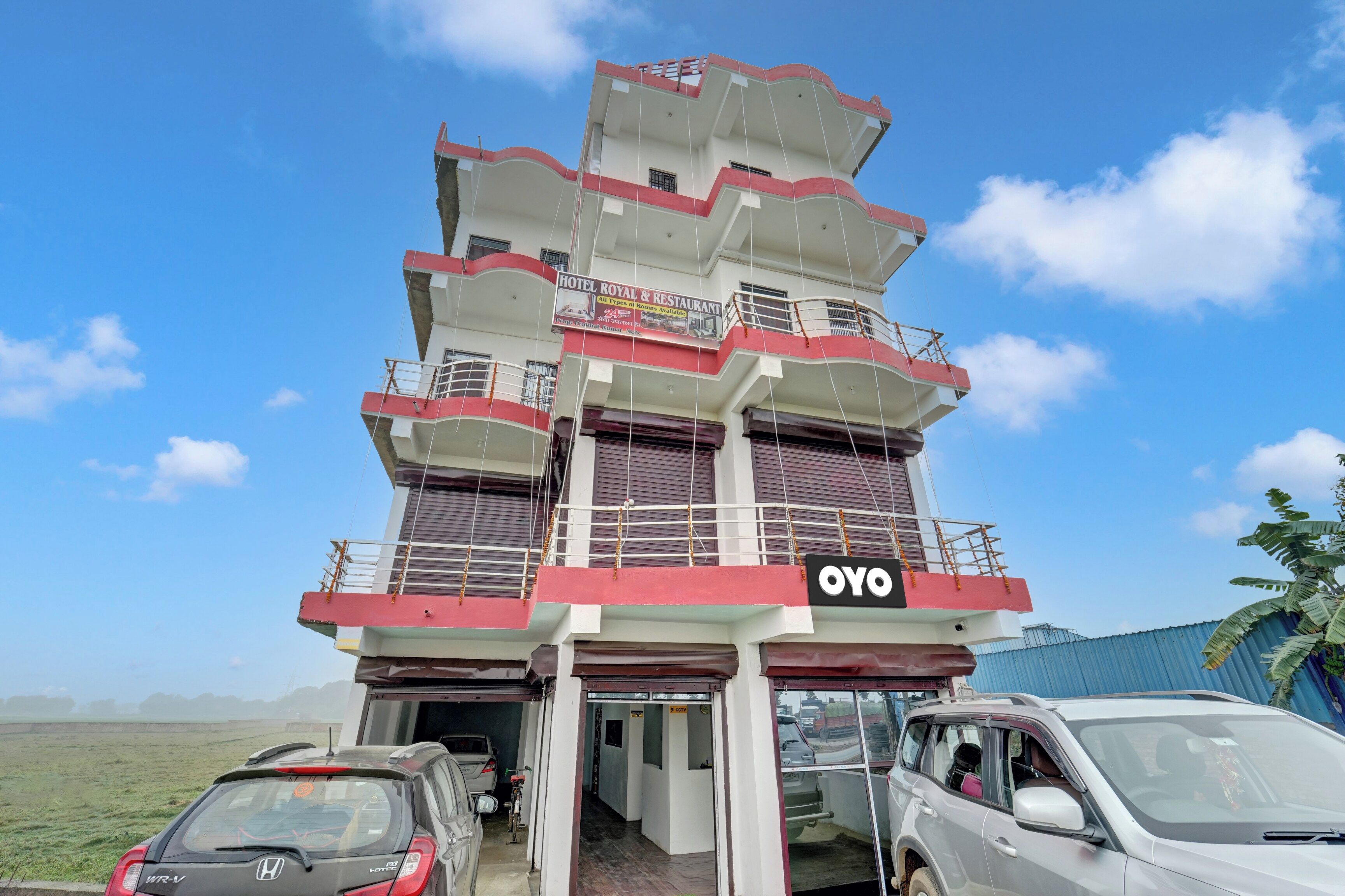 Un hotel de varios pisos con un llamativo letrero 'OYO', varios balcones y entrada principal al nivel de la calle.