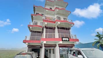 Un hotel de varios pisos con un llamativo letrero 'OYO', varios balcones y entrada principal al nivel de la calle.