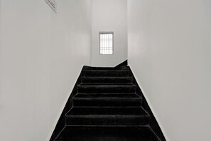 Un escalier menant à une fenêtre à carreaux, entourée de murs unis.