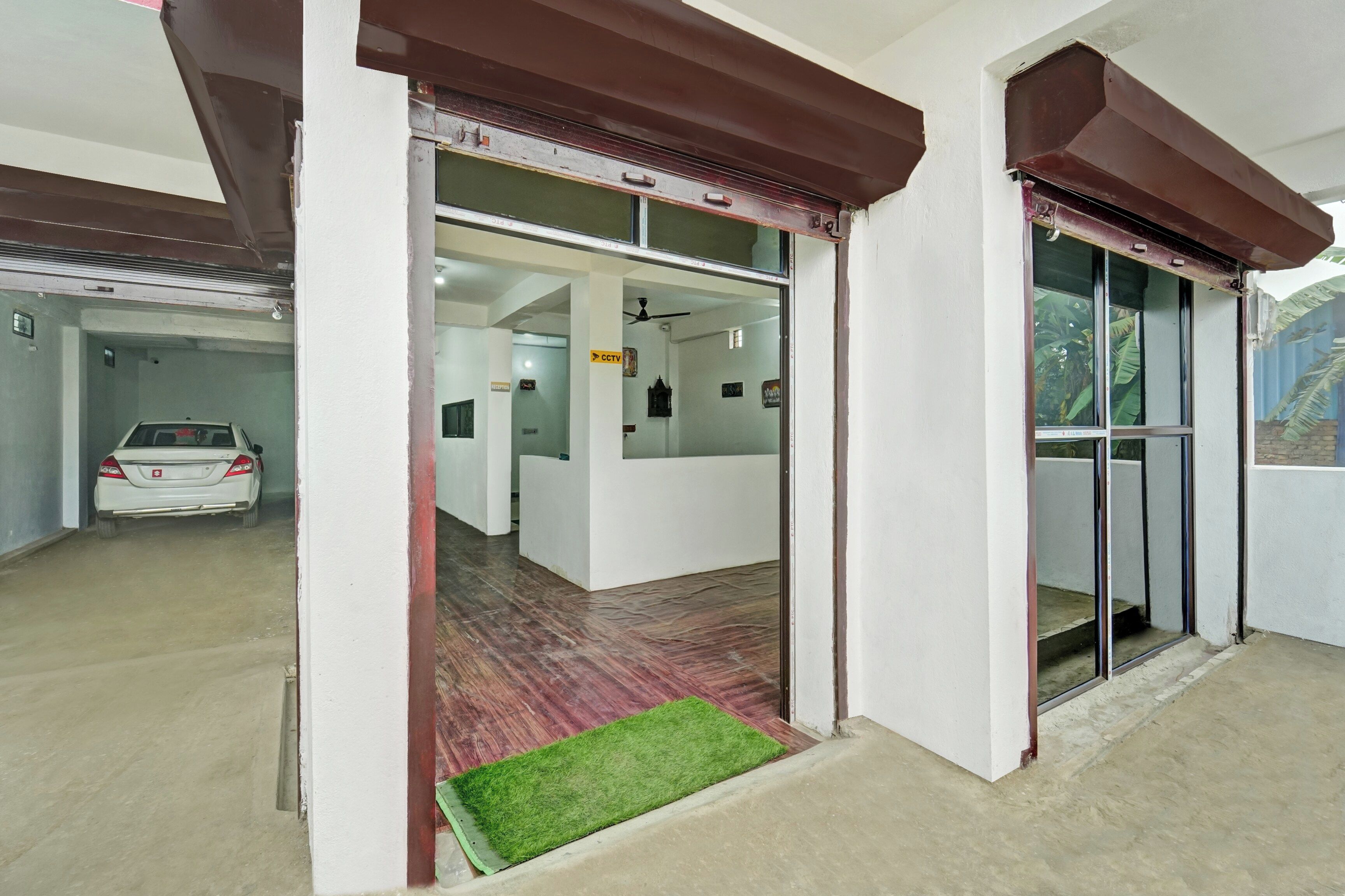 A reception area with a car parked outside, a CCTV sign, and a reception desk.