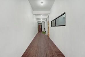 Un long couloir étroit, doté d’un plancher en bois et de murs blancs.
