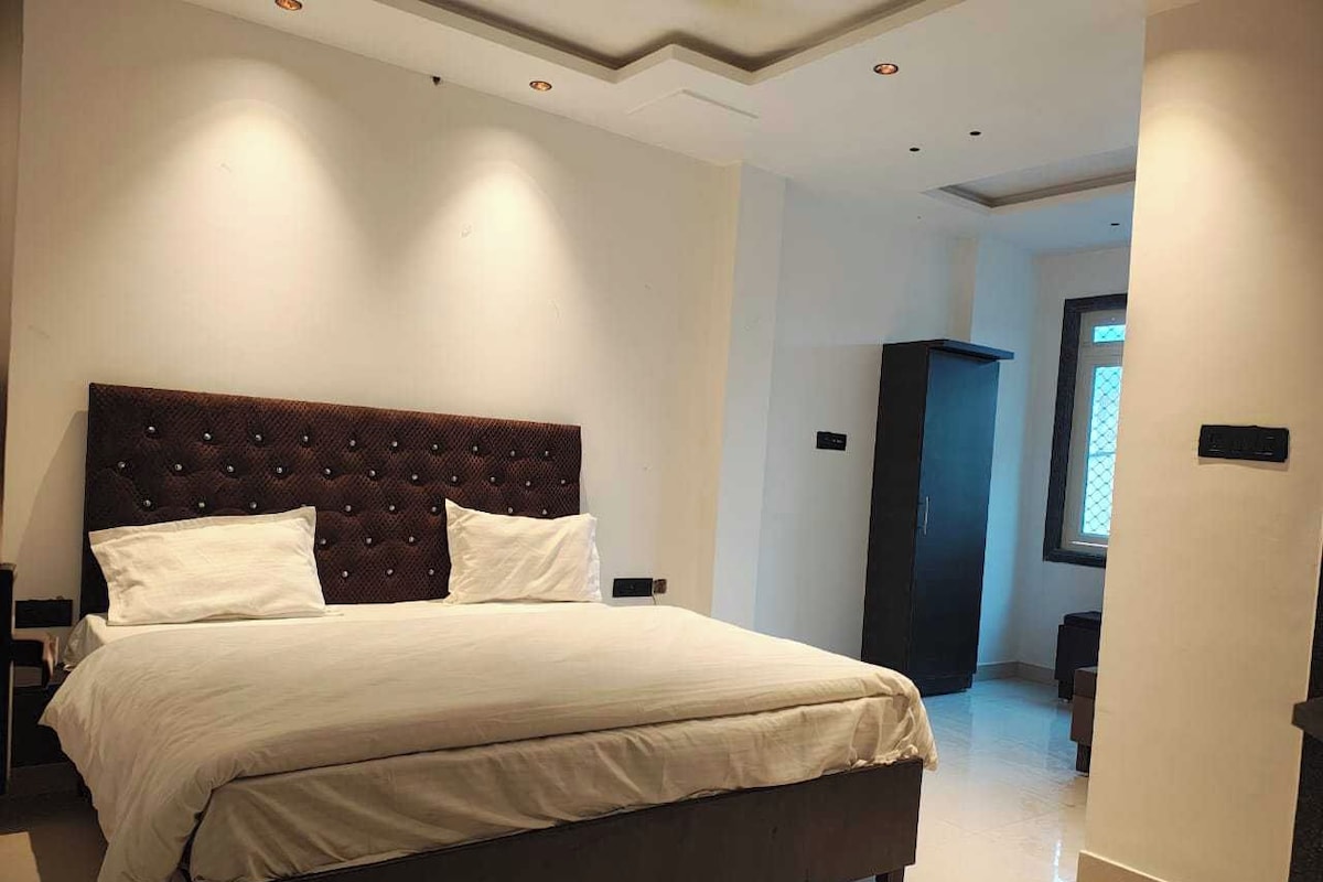 Une chambre à coucher moderne avec un grand lit, une tête de lit sombre et un dressing.