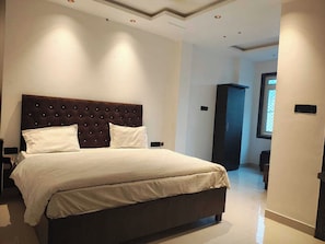 Une chambre à coucher moderne avec un grand lit, une tête de lit sombre et un dressing.