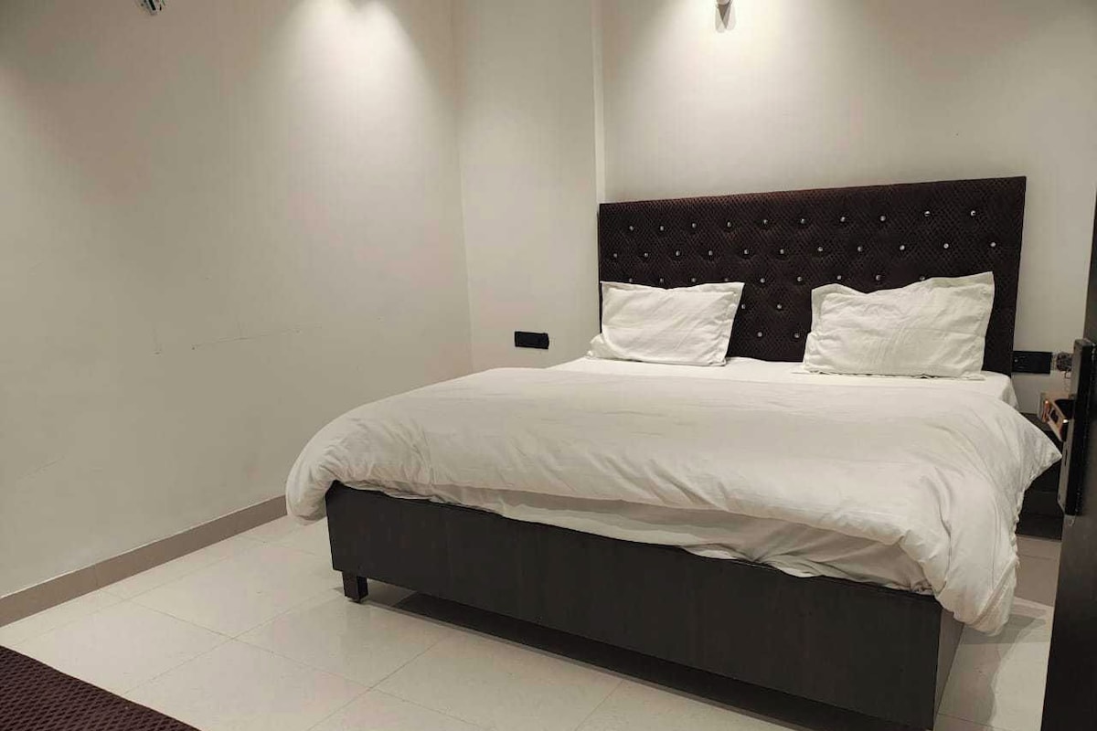 Un dormitorio moderno con una cama grande, un cabecero oscuro y un banco.