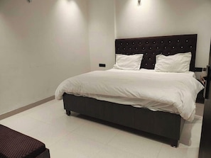 Une chambre à coucher moderne avec un grand lit, une tête de lit sombre et un banc.