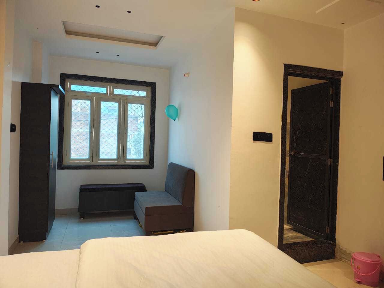 Ein Schlafzimmer mit einem Bett, einer Bank, einem Fenster und einer Tür.