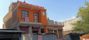 Un edificio de varios pisos con una fachada naranja llamativa, un letrero que dice 'Oyo Hotel' y un tanque de agua visible en el techo.
