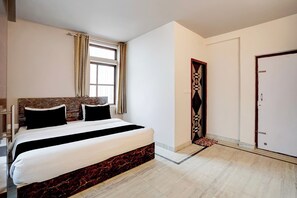 Quarto de hotel com cama, janela, porta e guarda-roupa.
