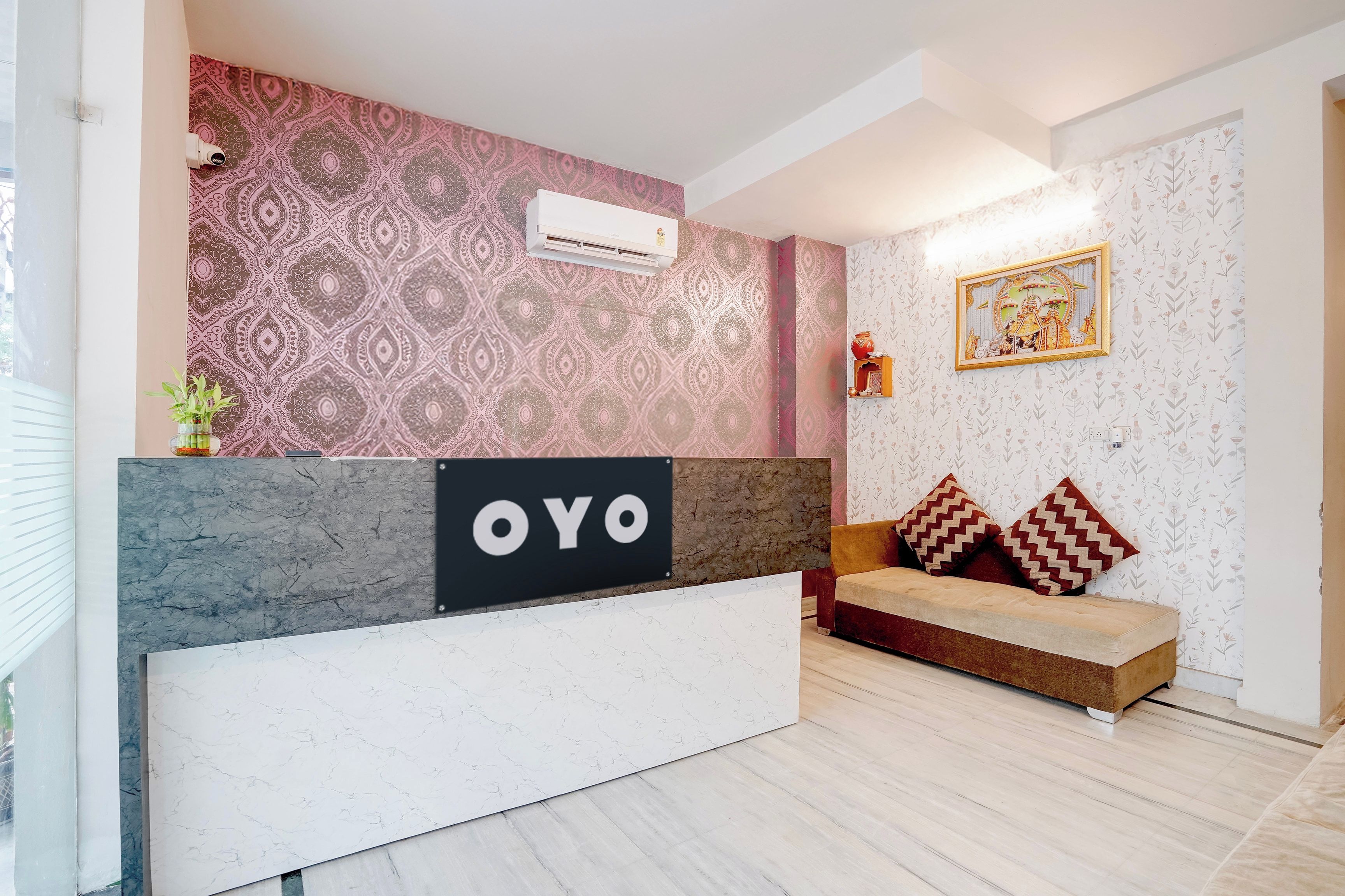 A reception area with a patterned wall, a marble reception desk, and a sofa with patterned cushions.