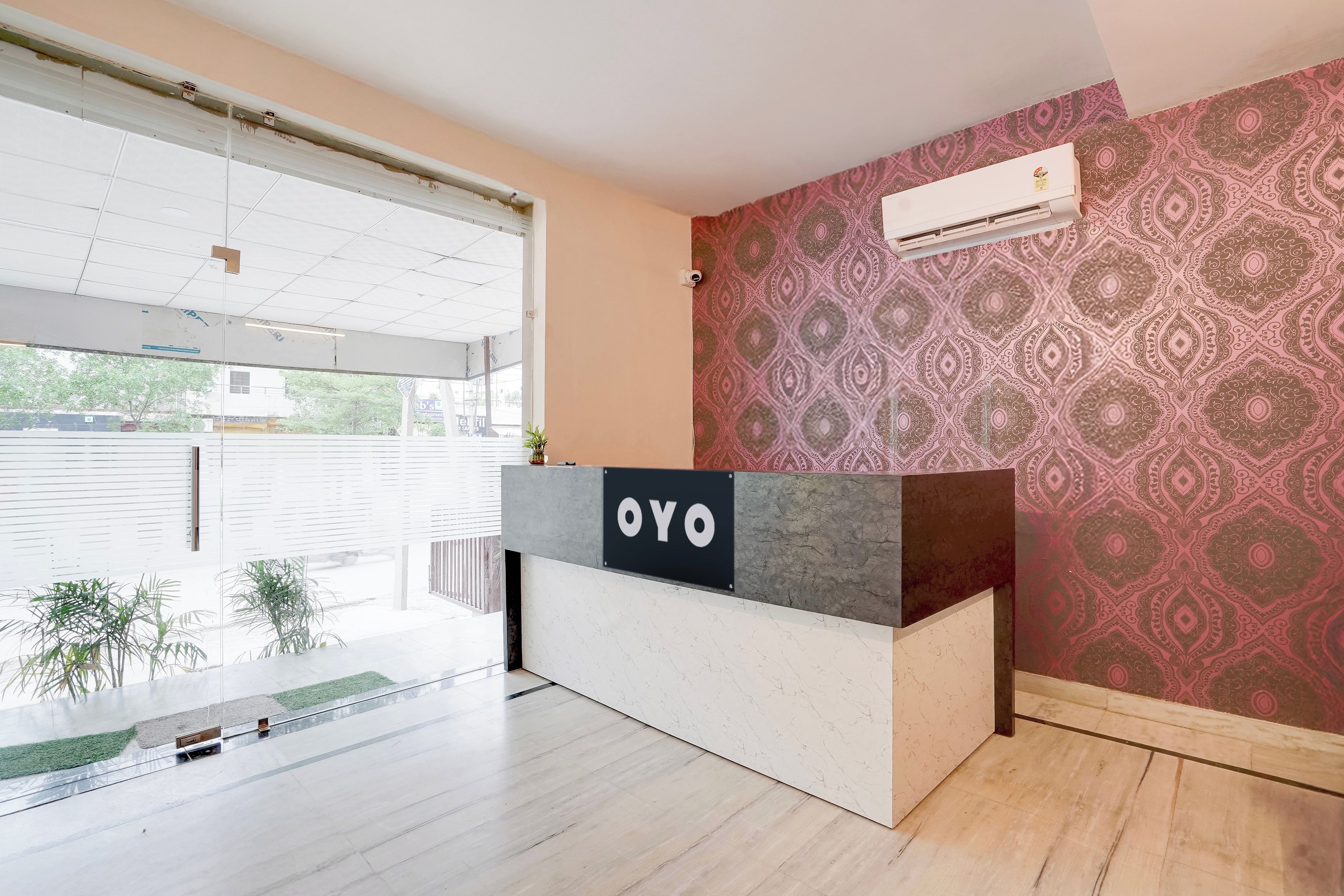 A reception desk with a 'YO' sign, a patterned wall, and an air conditioning unit.