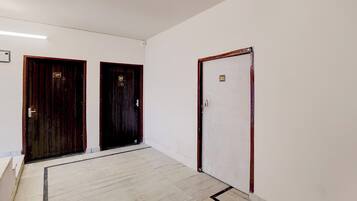 Un pasillo con tres puertas, dos de madera oscura y una blanca.