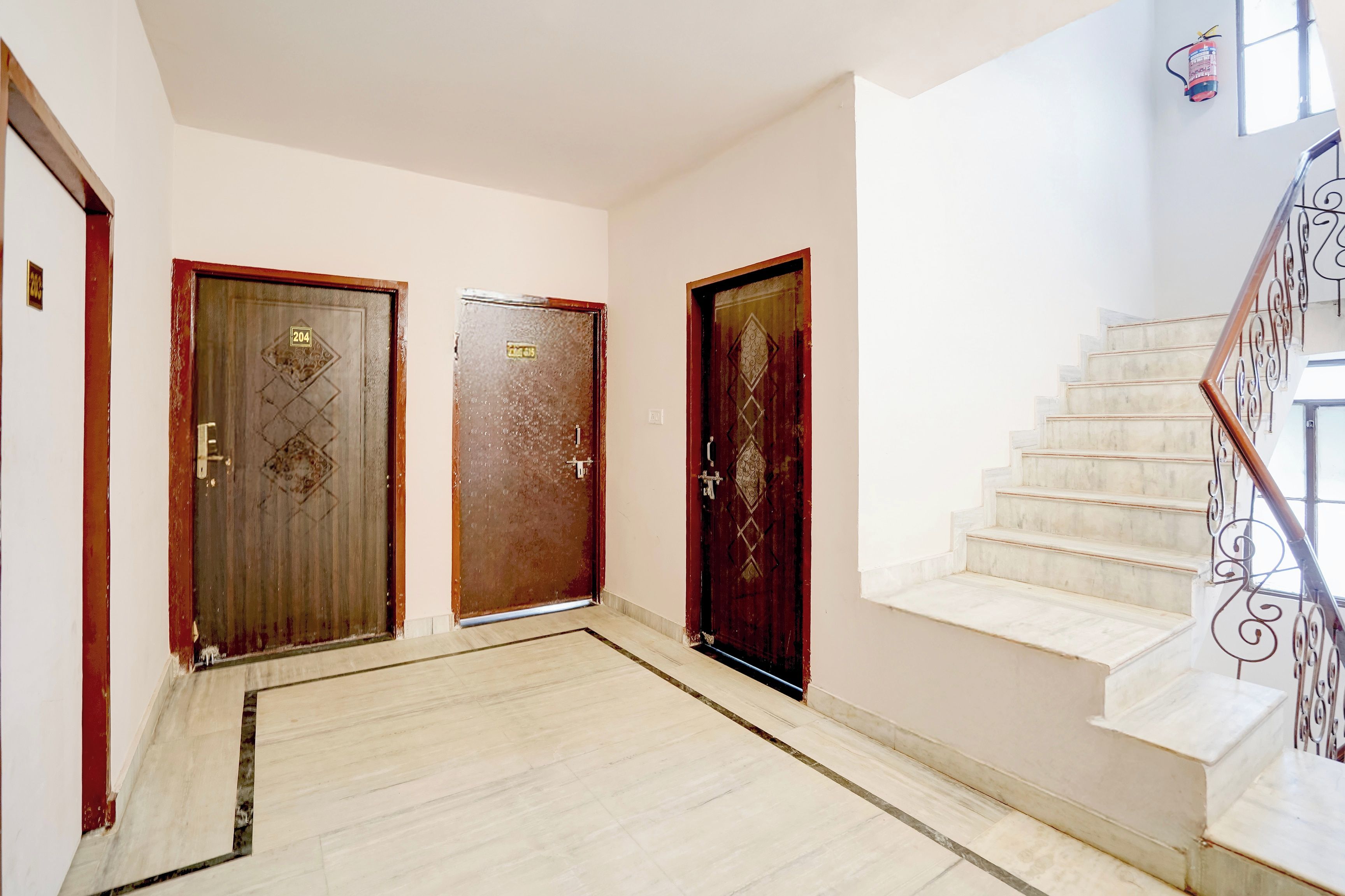 Un pasillo con dos puertas, una escalera y un extintor.