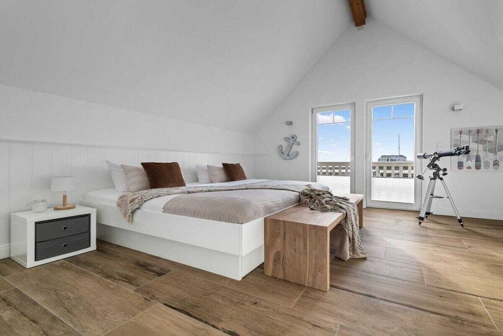 A bedroom with a bed, bedside table, and a telescope.