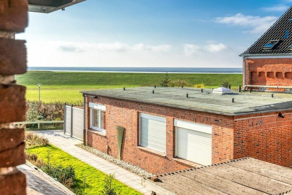 A brick building with a flat roof, a garage, and a view of the ocean.
