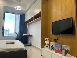 Una habitación de hotel con una cama, un escritorio, un televisor y vistas a la ciudad.