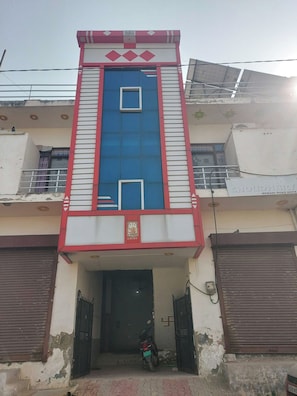 Un edificio con fachada central azul y roja, una entrada con puerta y una motocicleta a la vista.