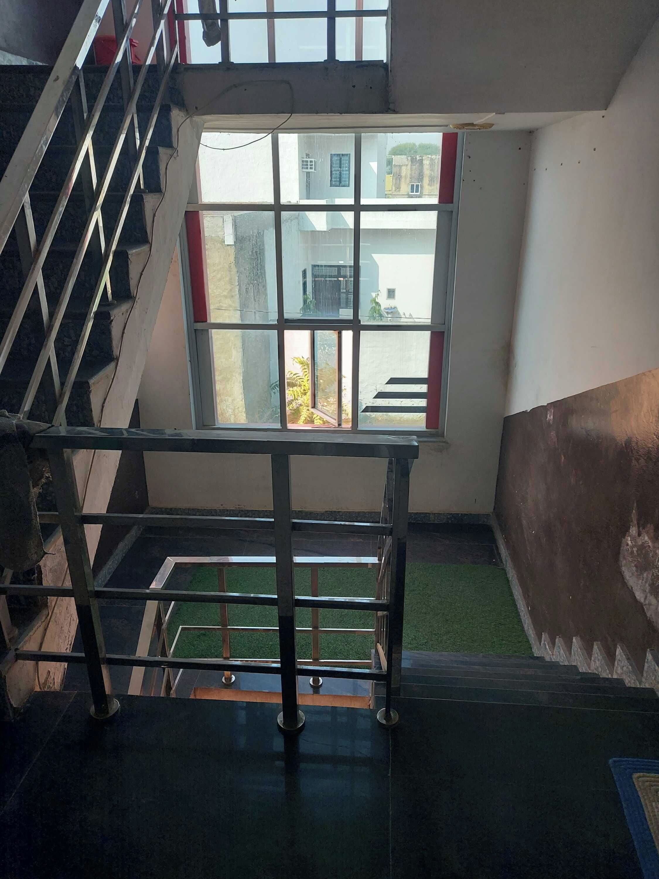A staircase with a metal railing leading to a landing with a view of a building outside.