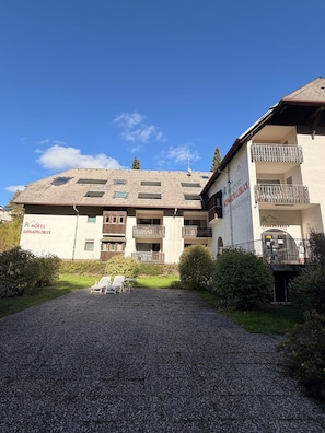A hotel with multiple balconies, a gravel driveway, and a clear sky. - Modern 2-Room Holiday Apartments Triberg (Triberg im Schwarzwald)