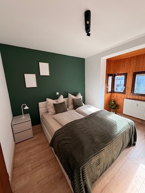 A bedroom with a bed, bedside table, and a green wall. - Modern 2-Room Holiday Apartments Triberg (Triberg im Schwarzwald)