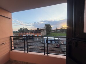 Un balcon doté d’une rambarde en métal, donnant sur un chantier de construction et des immeubles.