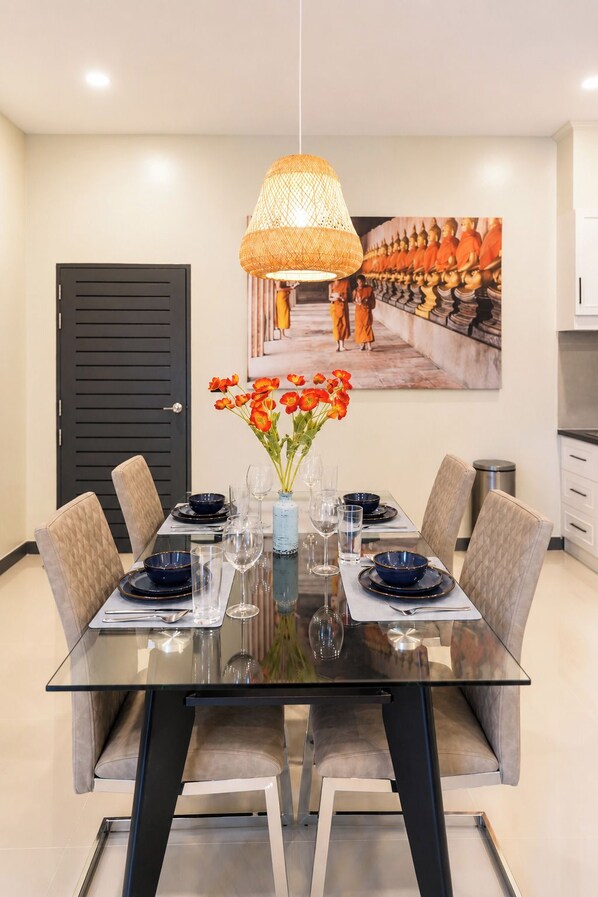 A dining area with a glass table, chairs, and a vase of flowers.