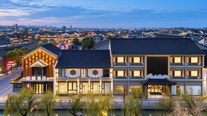 A hotel with traditional architecture, a modern building adjacent to it, and a view of a cityscape in the background. - Heyi Hotel (Huai'an)