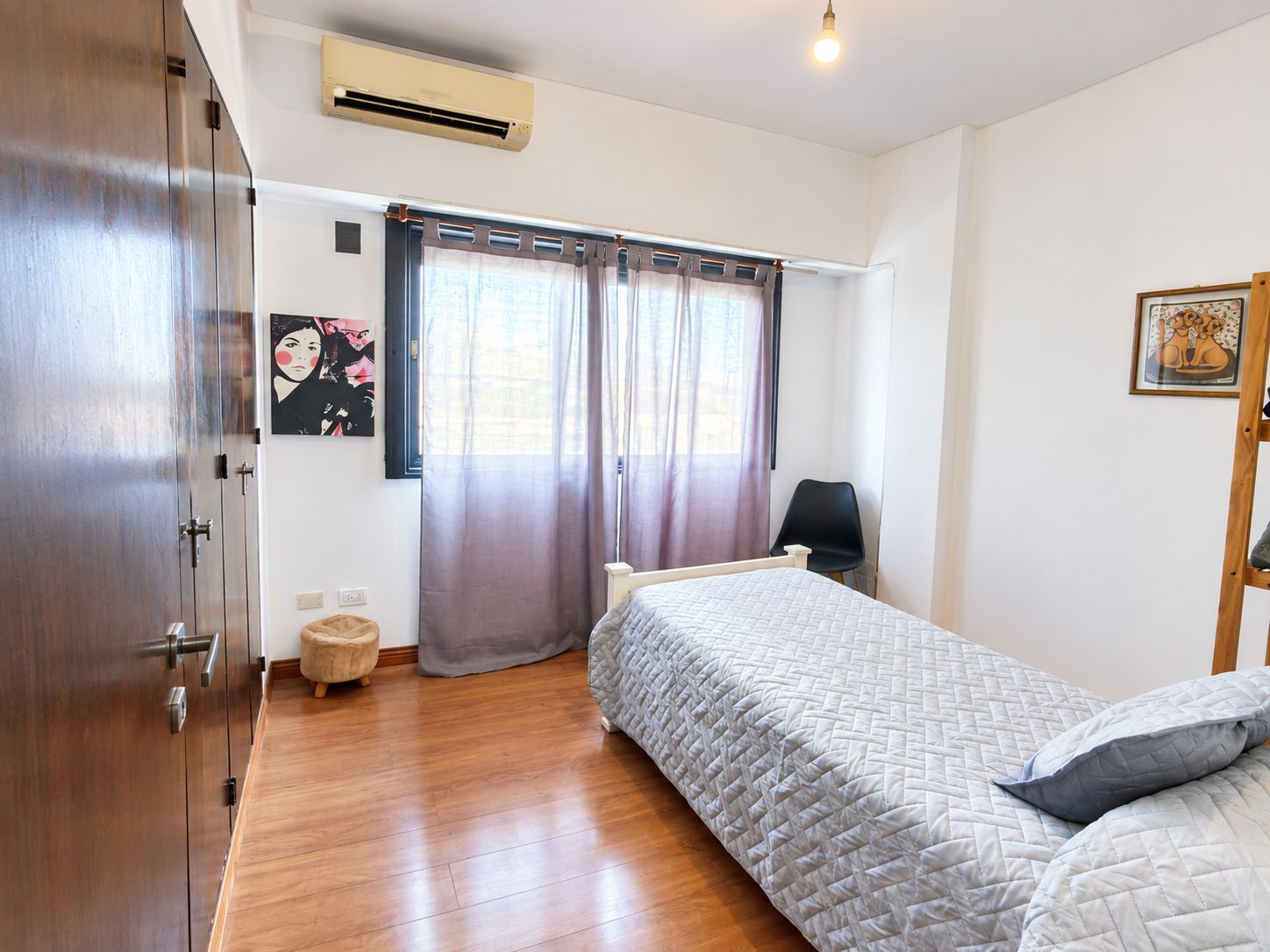 Une chambre à coucher avec un lit, une chaise, une armoire et une fenêtre avec des rideaux.