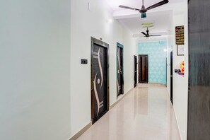 Pasillo de hotel con ventilador de techo, zona de recepción y cartel que prohíbe fumar.