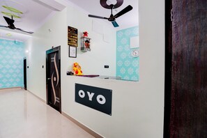 A reception area with a reception desk, a clock, a ceiling fan, and a wall-mounted sign. - Hotel O Mahadev Palace (Patna)