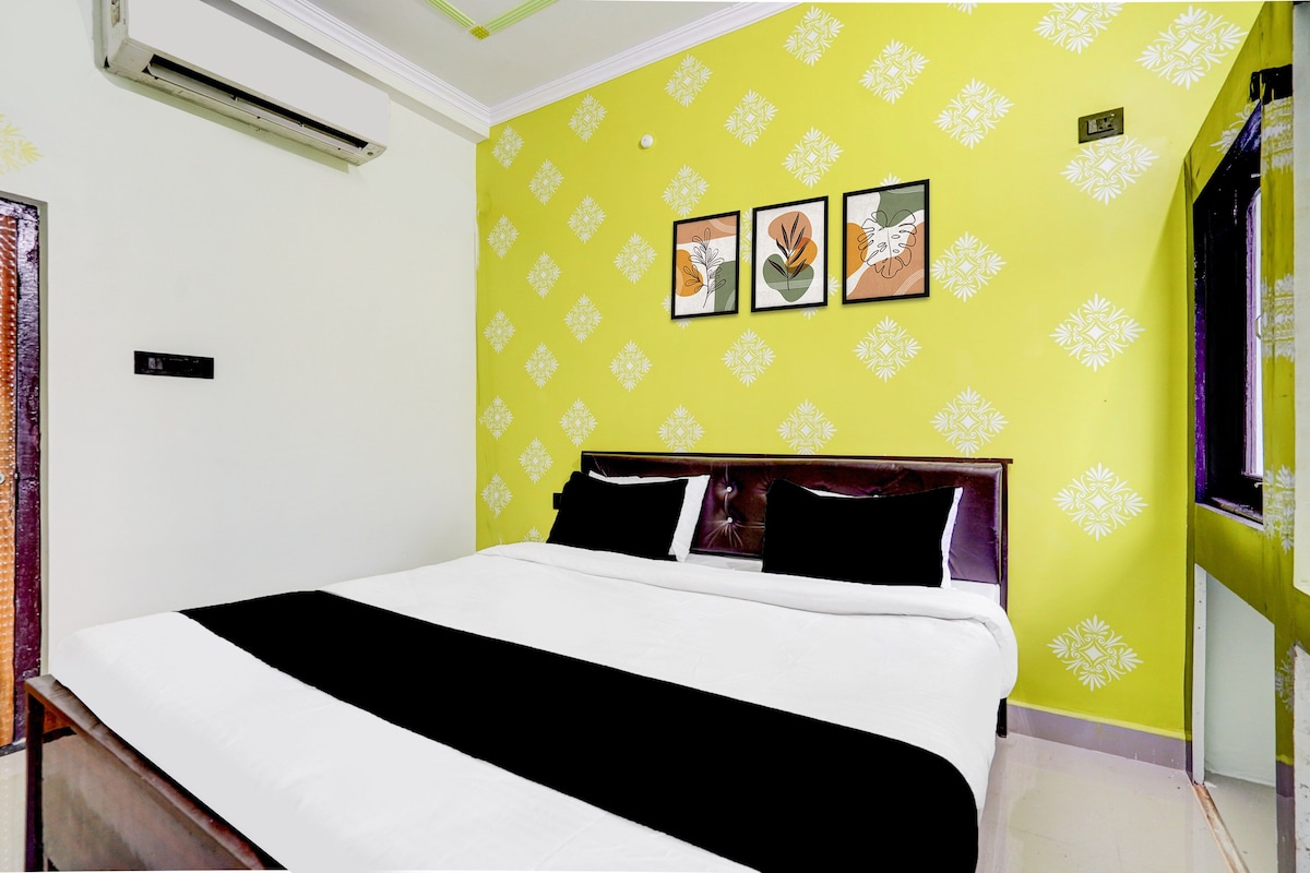 A hotel room with a bed, a wall with a geometric pattern, and three framed artworks.