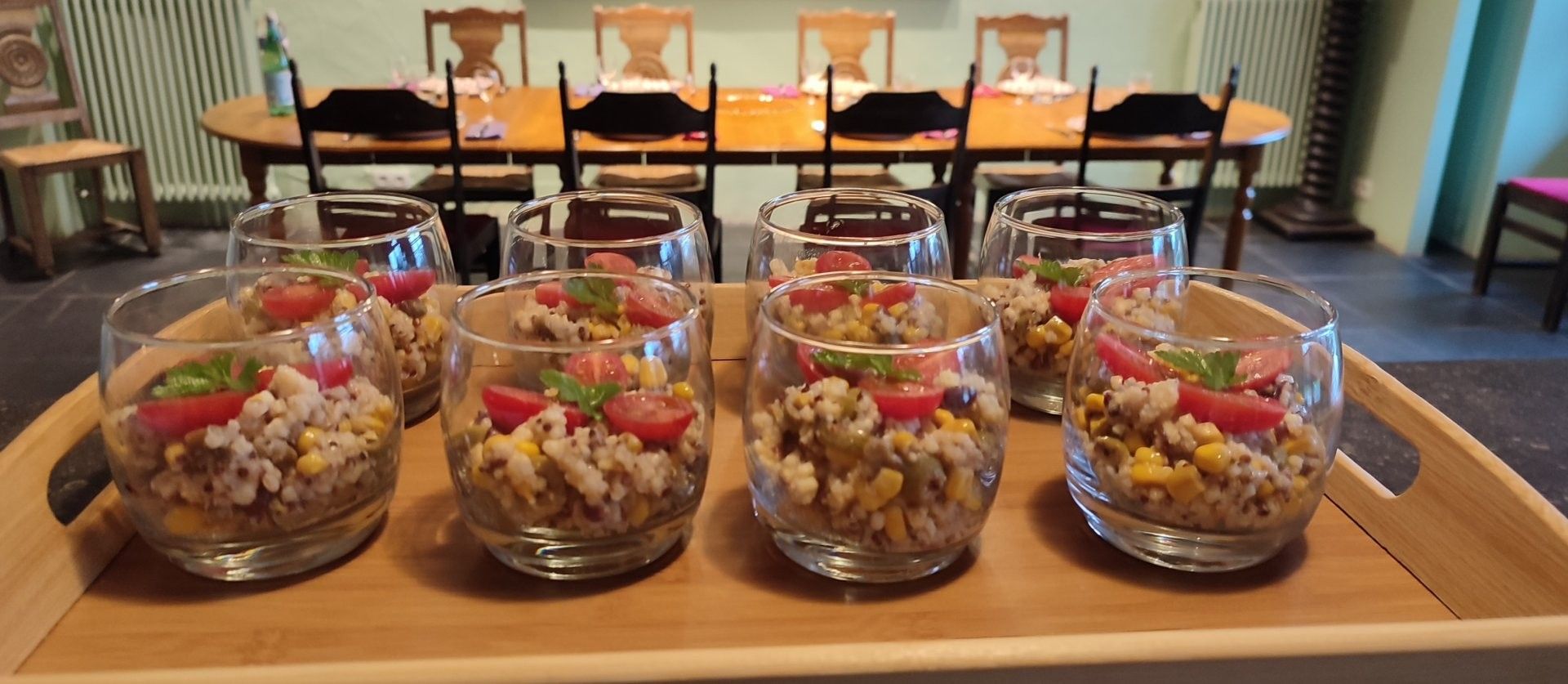 A dining table set with multiple glasses containing a rice-based dish, garnished with tomatoes and herbs, in a restaurant setting.