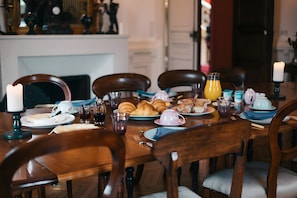 Taula de dinar a punt, amb plats, gots i diferents aliments, com ara pastissos i una espelma.