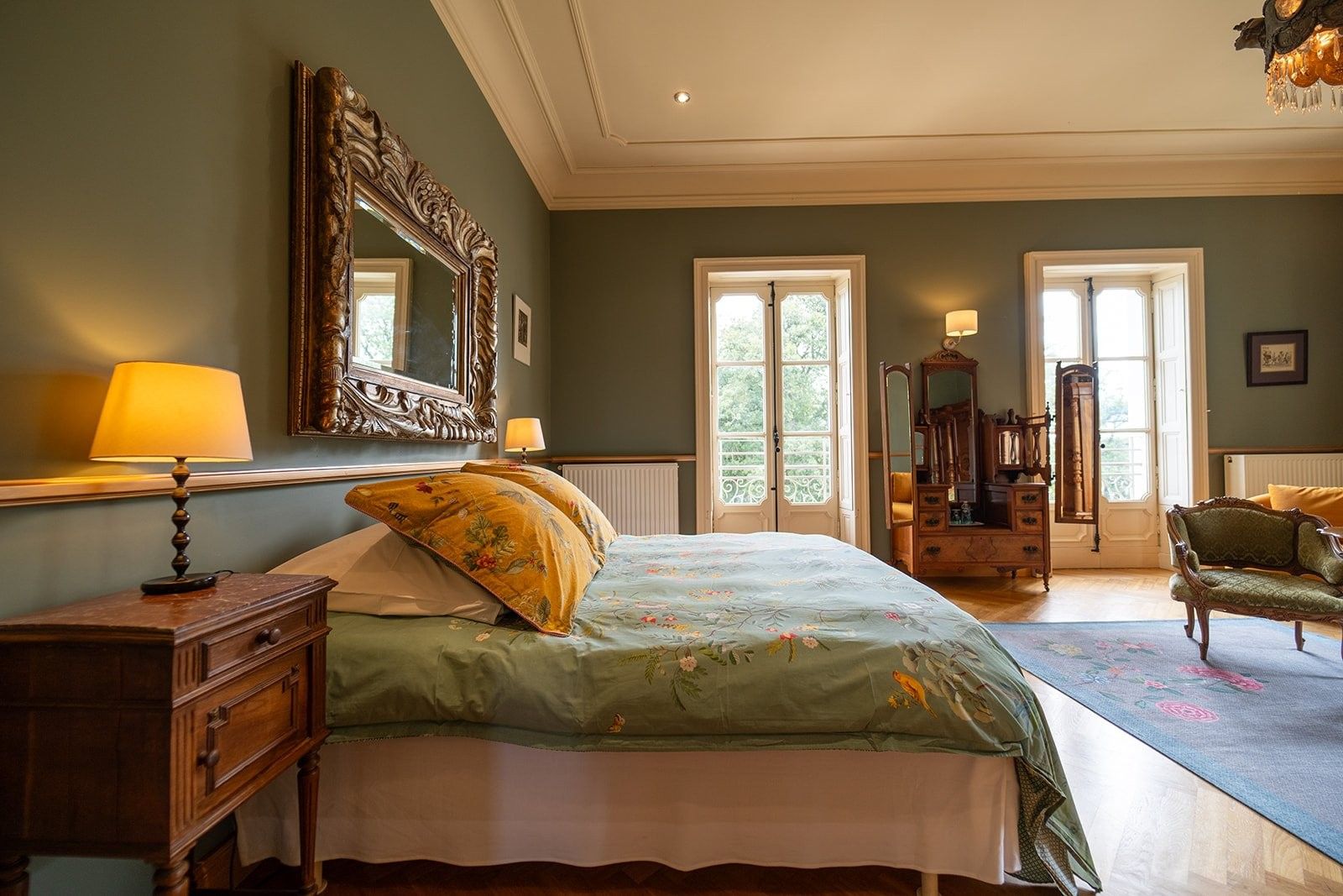 A bedroom with a bed, dresser, mirror, and a view of the outdoors through a door.