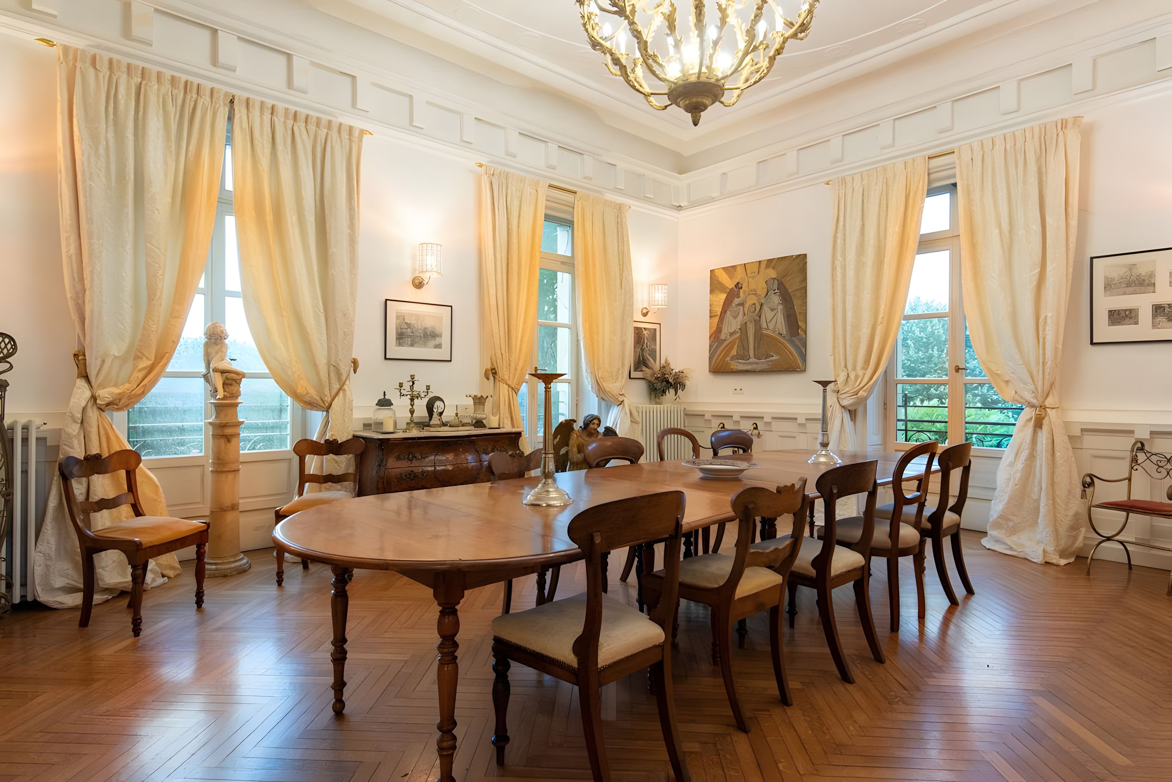 Une salle à manger élégante, dotée d’une grande table en bois, de nombreuses chaises et d’un décor classique.