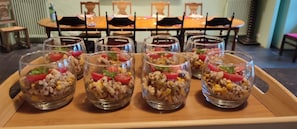 Taula de dinar coberta amb diversos vasos amb un plat a base de rice, decorat amb tomàquets i herbes, en un ambient de restaurant.