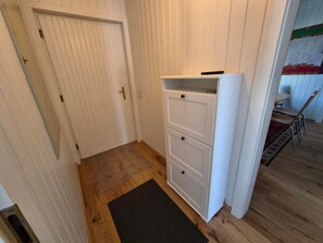 A narrow hallway with a white door, a white cabinet with drawers, and a black doormat on the wooden floor. - Holiday Home 'Haus Hovilin' with Private Terrace, Private Garden and Wi-Fi (Höflein bei Bruck an der Leitha)