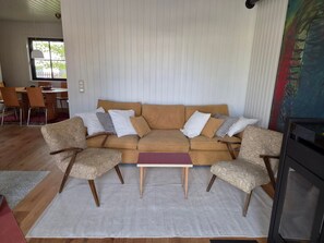 Ein Wohnzimmer mit einer Sofagarnitur, zwei Sesseln, einem Couchtisch und einem Kamin.