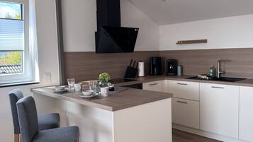 A modern kitchen with a central island, white cabinetry, and a black range hood.