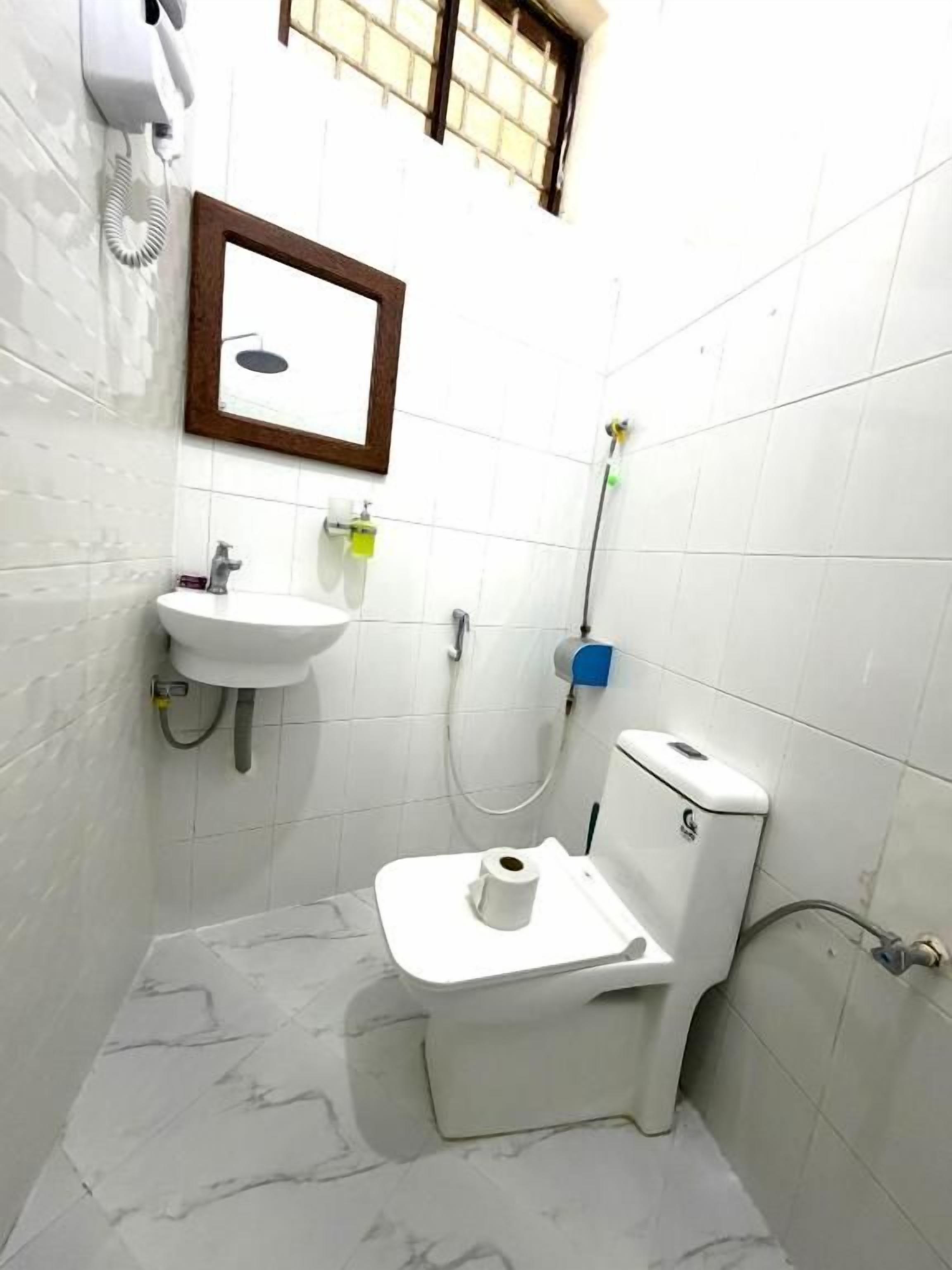 A small bathroom with a toilet, sink, and a mirror.