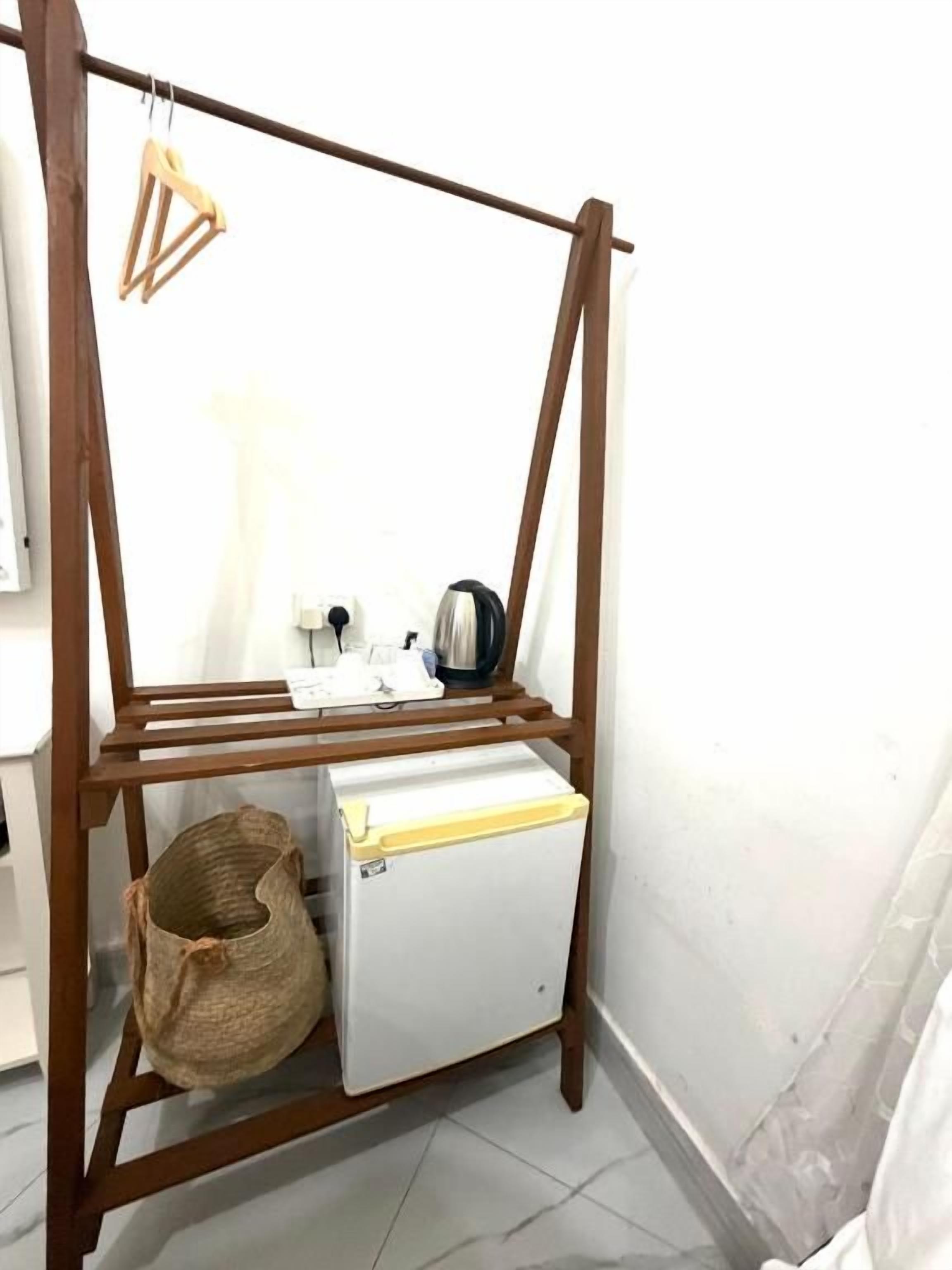 A corner room with a wooden wardrobe, a small white appliance, and a woven basket.