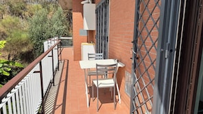 A balcony with a table and chairs, a brick wall, and a metal gate. - New Listing (Roma)