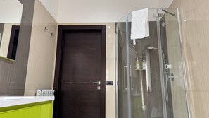 A modern bathroom with a glass shower enclosure, a wooden door, and a green vanity. - New Listing (Roma)