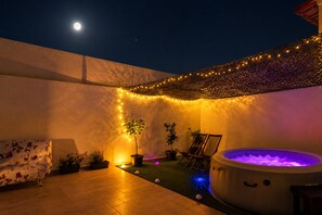 Eine Terrasse mit Whirlpool, Lichterketten und Blumentöpfen.