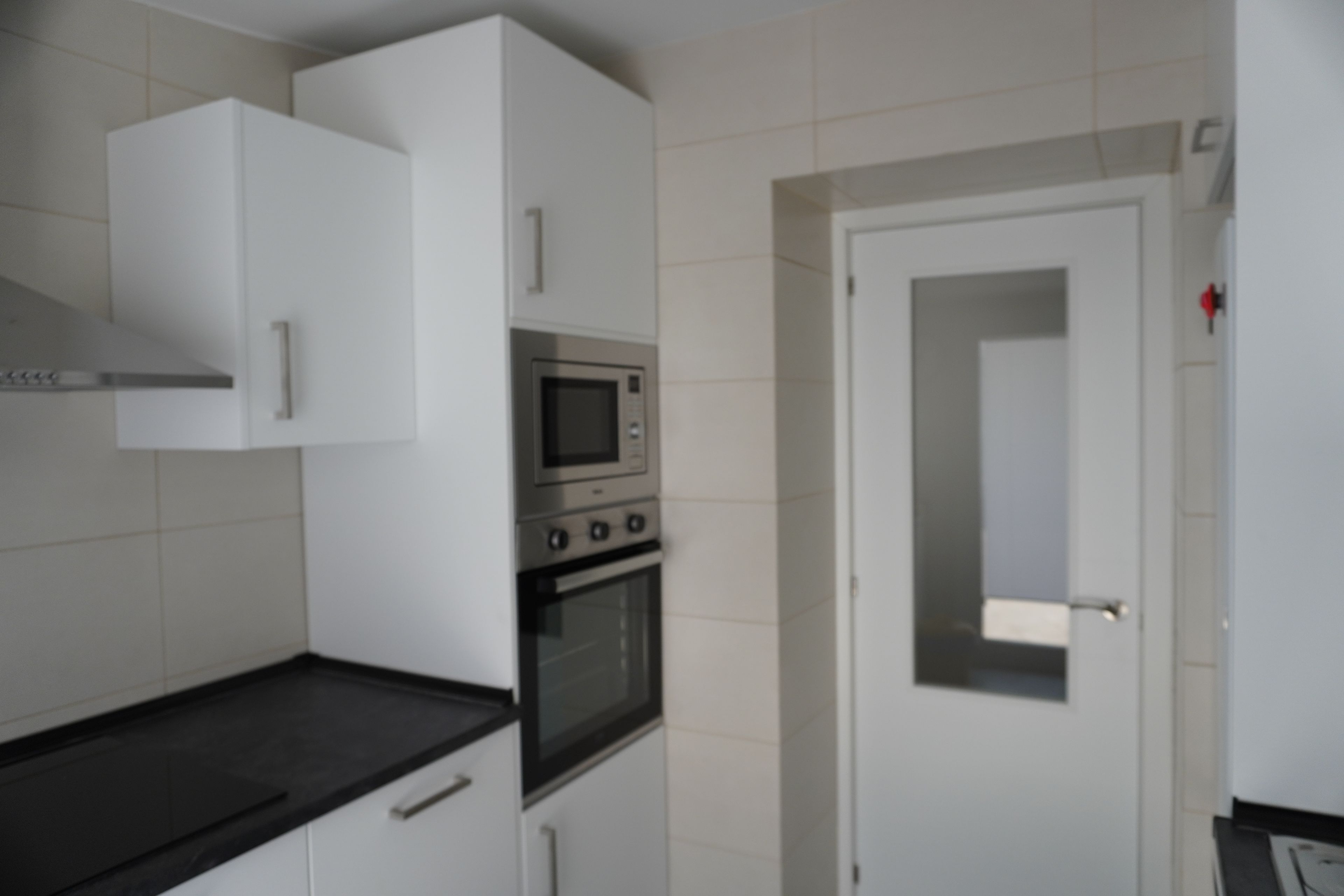 A kitchen with white cabinets, a microwave, and an oven.