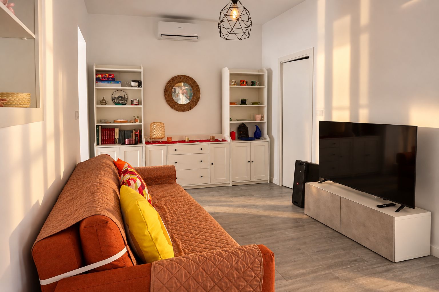 Een moderne woonkamer met een bank, een flatscreen televisie en inbouwmeubels.
