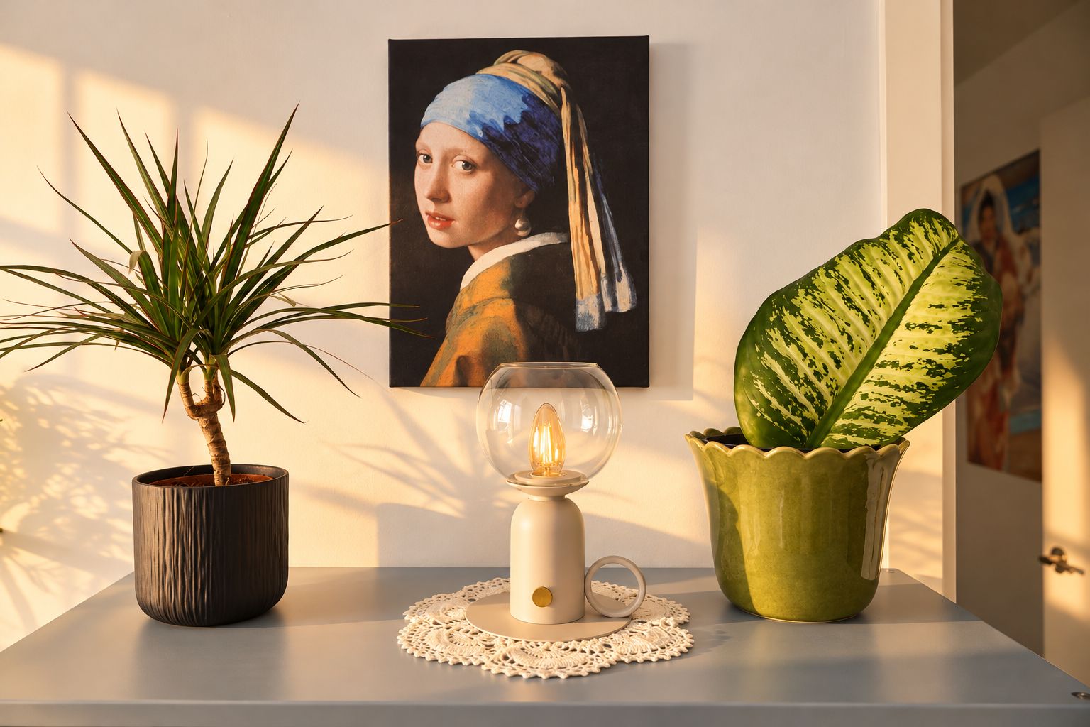 Une plante en pot, une lampe de table et une œuvre d’art encadrée accrochée au mur.