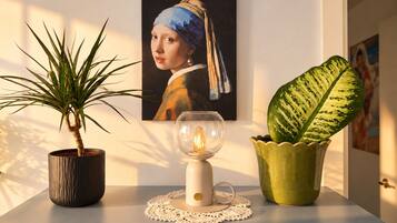 Une plante en pot, une lampe de table et une œuvre d’art encadrée accrochée au mur.